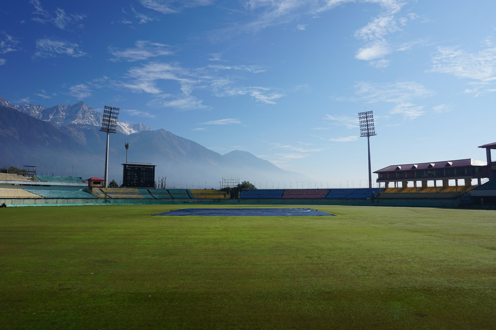 green grass field near mountain under blue sky during daytime